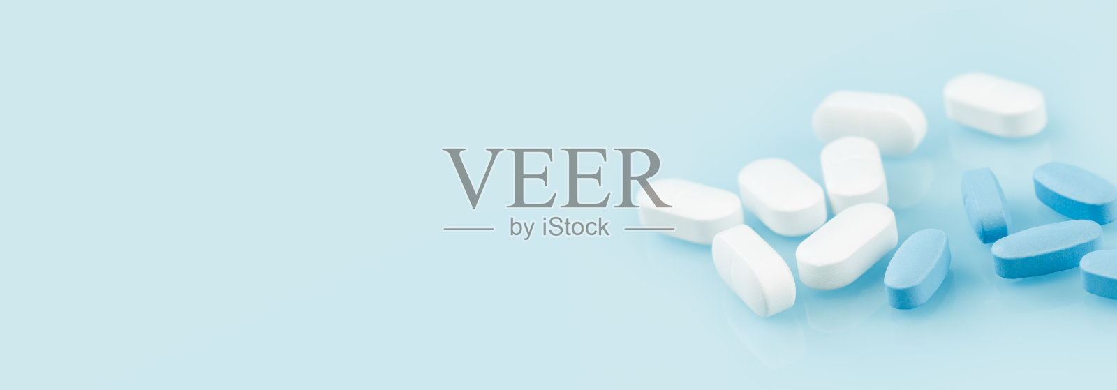 几片白色和蓝色的药片或药丸在桌子上。医学和药学照片摄影图片