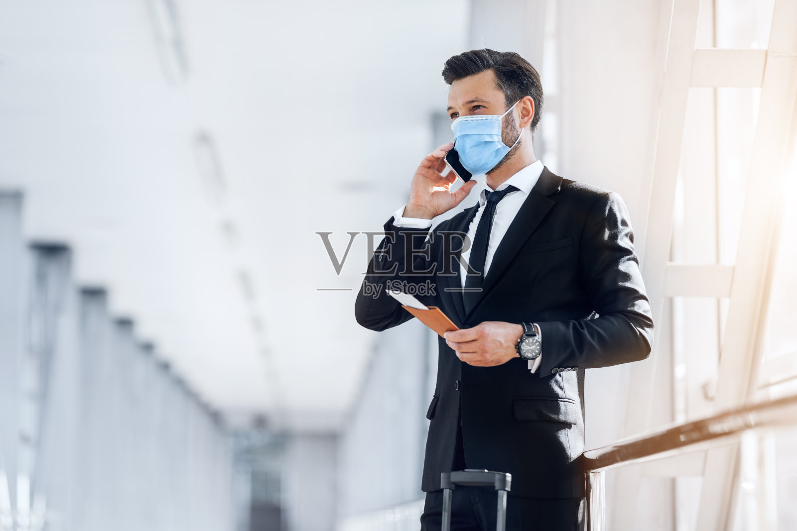 一个穿着西装，拿着护照，拿着机票，打电话的人照片摄影图片