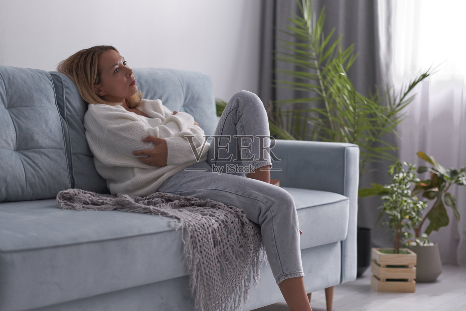 一个悲伤的女人坐在客厅的沙发上。失意迷茫的女性觉得私生活中有不愉快的问题，与男友吵架分手照片摄影图片