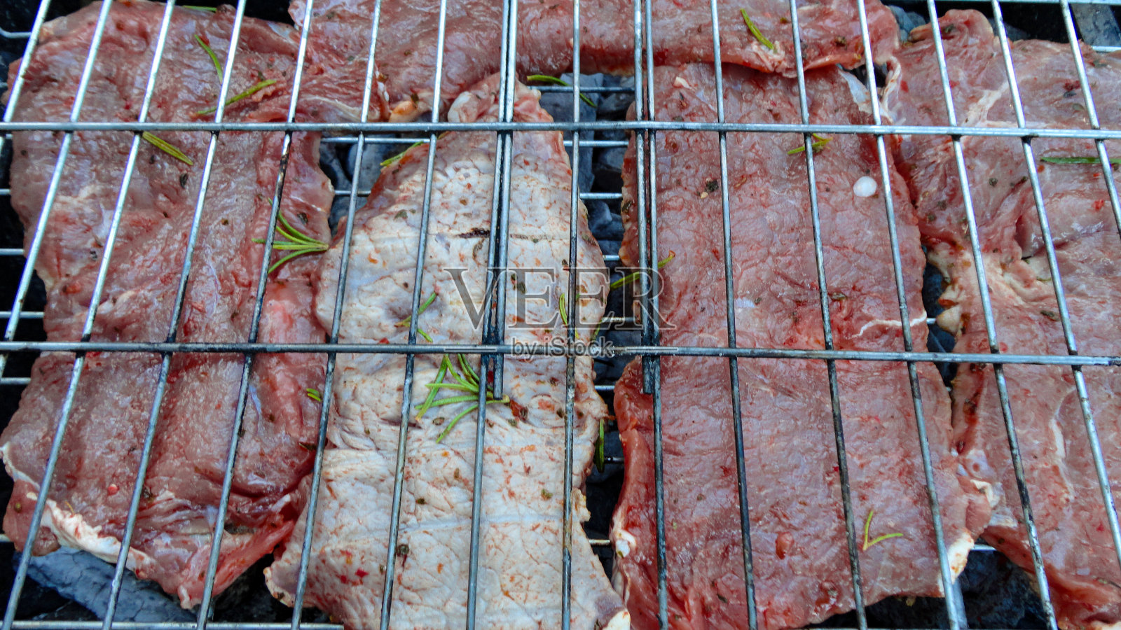 牛排烧烤与牛肉在金属烤架上，在热炭上。照片摄影图片