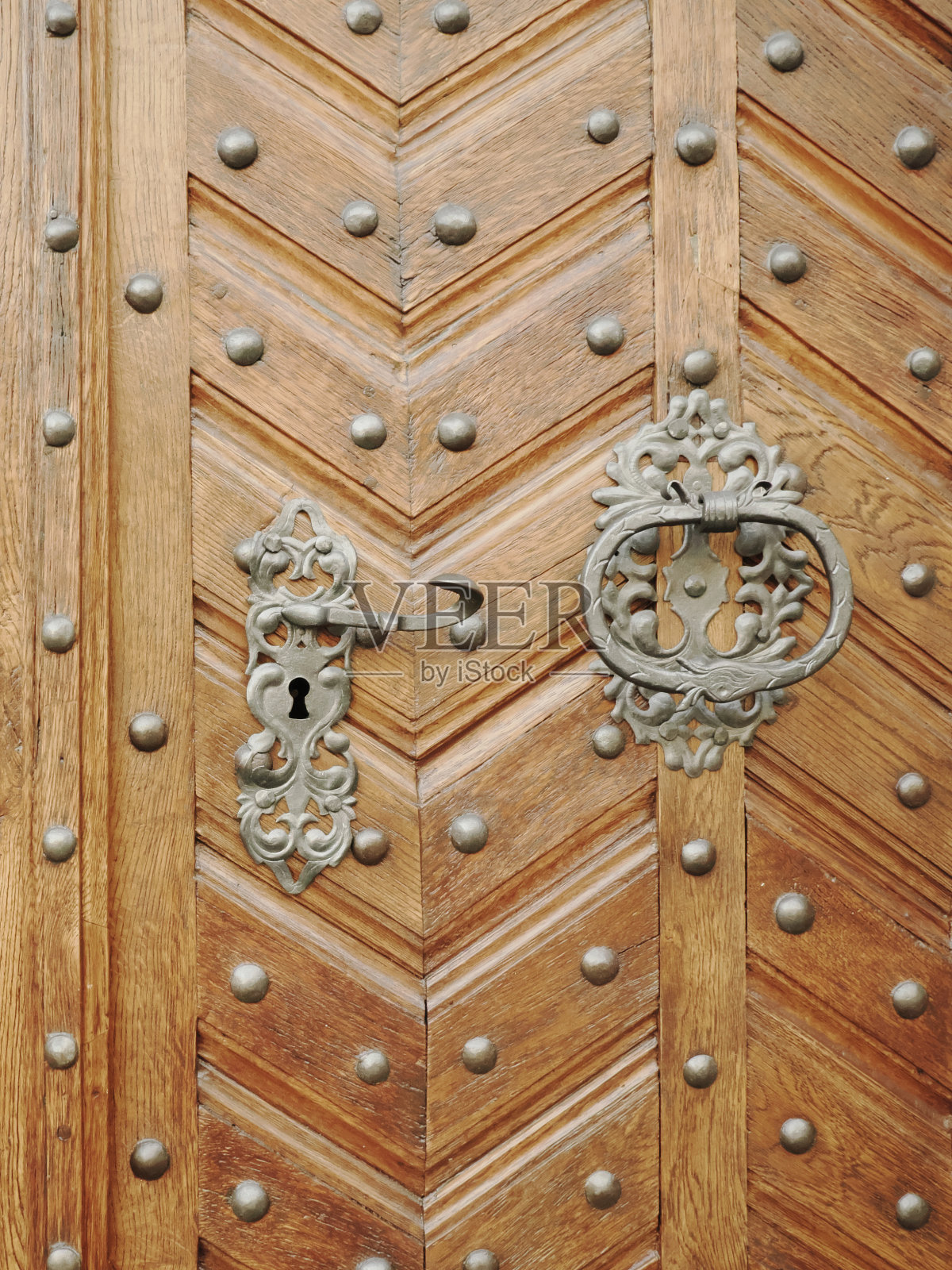 带铆钉的旧木门。金属把手和门锁。照片摄影图片