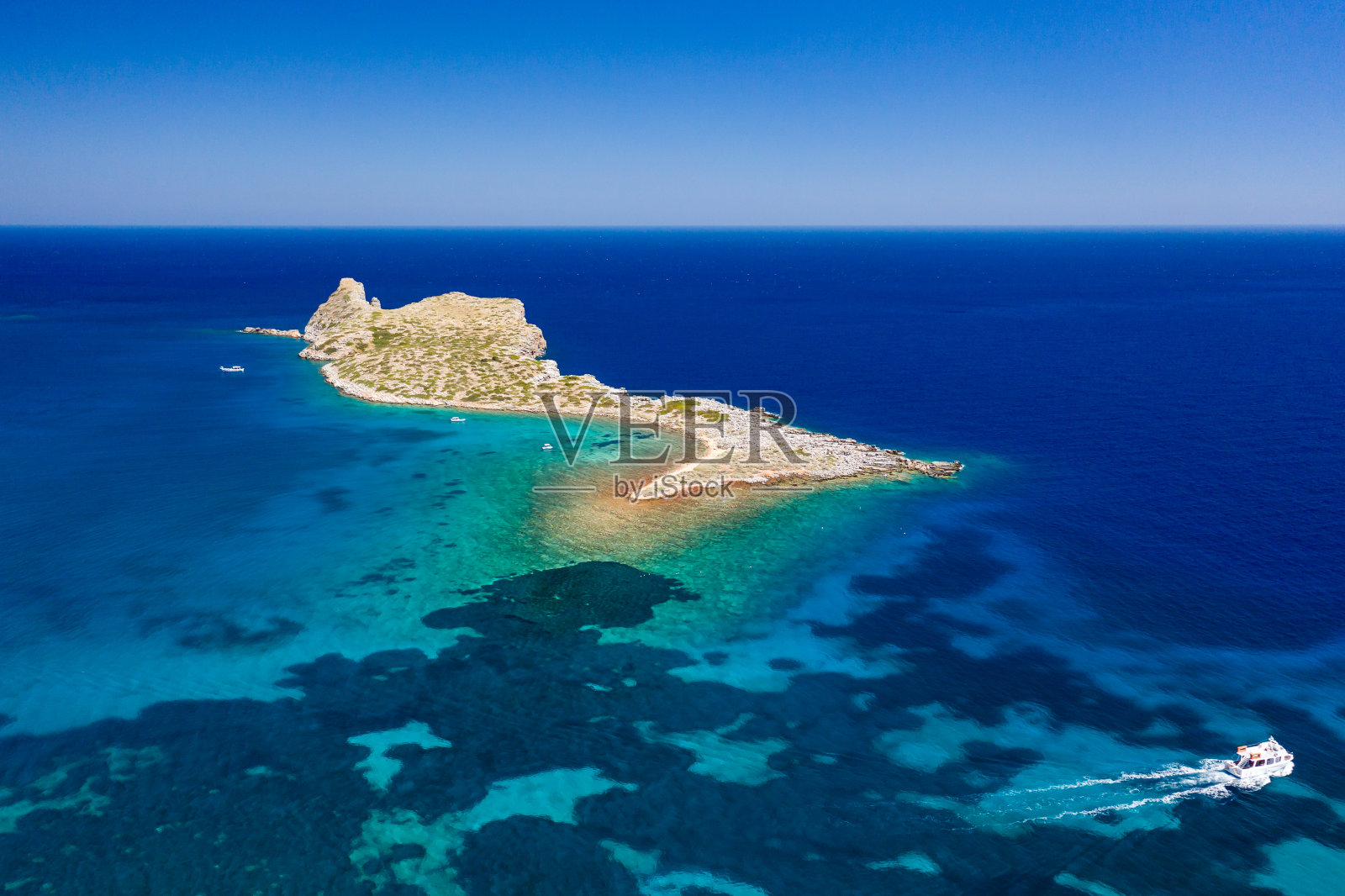 在清澈湛蓝的海洋中鸟瞰一个小岛和小船(克洛基塔，埃隆达，克里特岛，希腊)照片摄影图片
