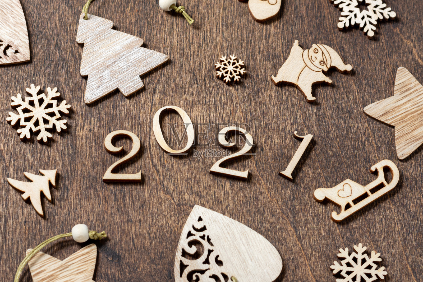 2021年新年快乐。木制的圣诞节或新年装饰在木制的棕色背景上。圣诞背景与木制数字2021。生态装饰照片摄影图片