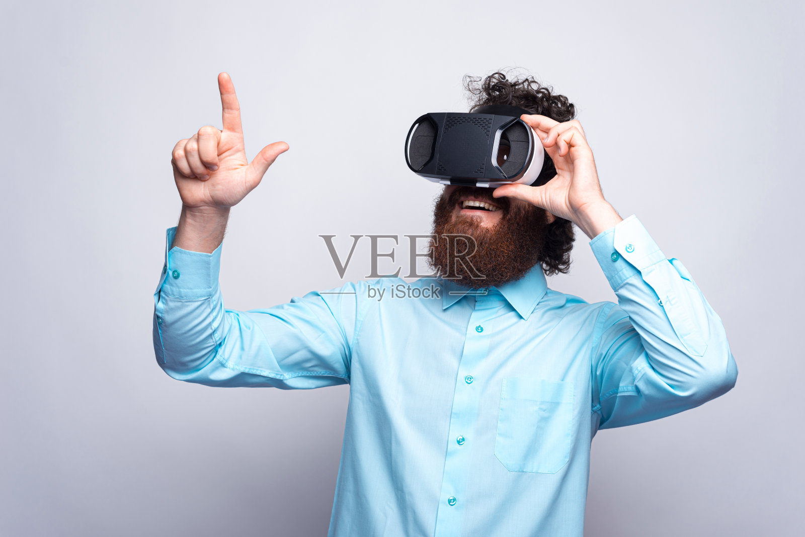 身穿蓝色衬衫、戴着虚拟现实眼镜的大胡子男子的照片照片摄影图片