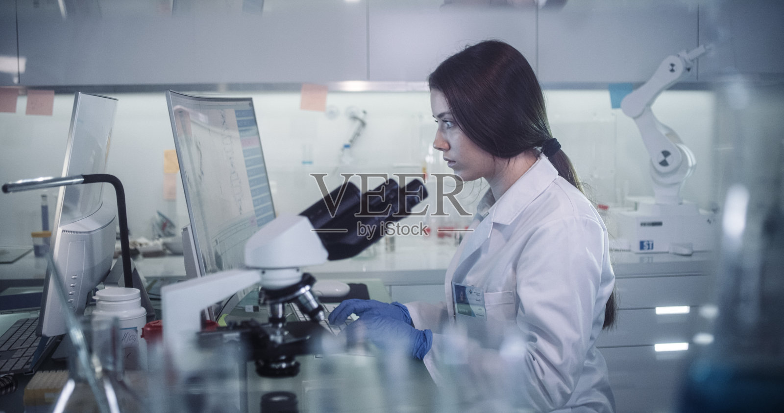 在未来实验室工作的女科学家。透过玻璃器皿照片摄影图片