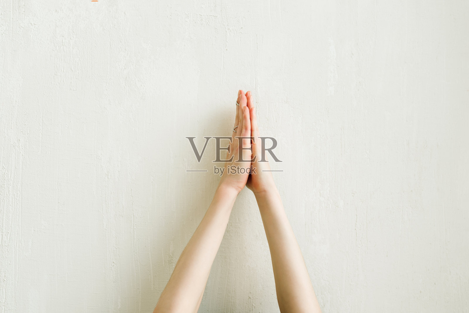 女人在白墙上做合十礼的手照片摄影图片