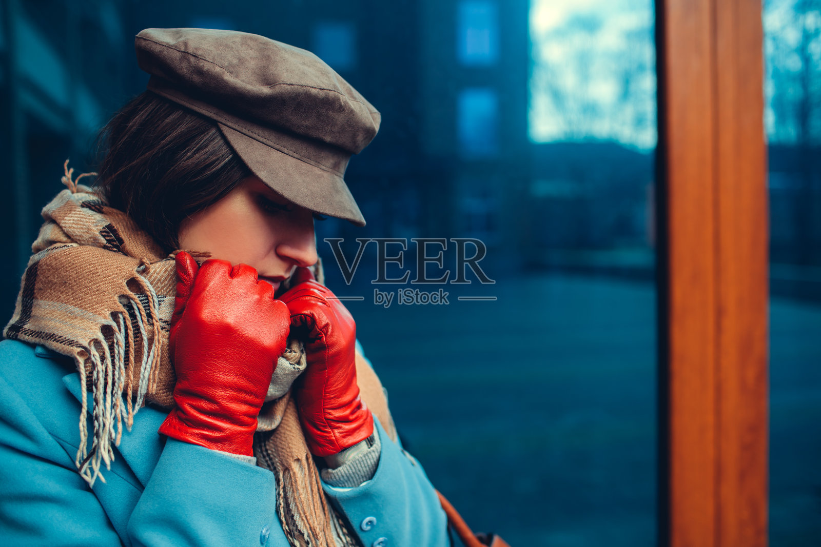 年轻女子穿着蓝色外套，戴着帽子和手套。春季女性服饰配饰。时尚照片摄影图片