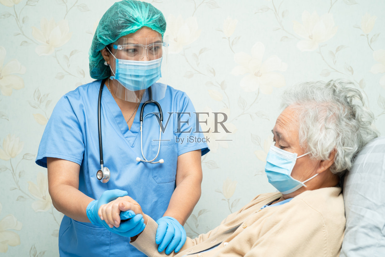 亚洲医生戴口罩和防护服新常态检查患者保护安全感染新冠肺炎疫情在隔离护理医院病房。照片摄影图片