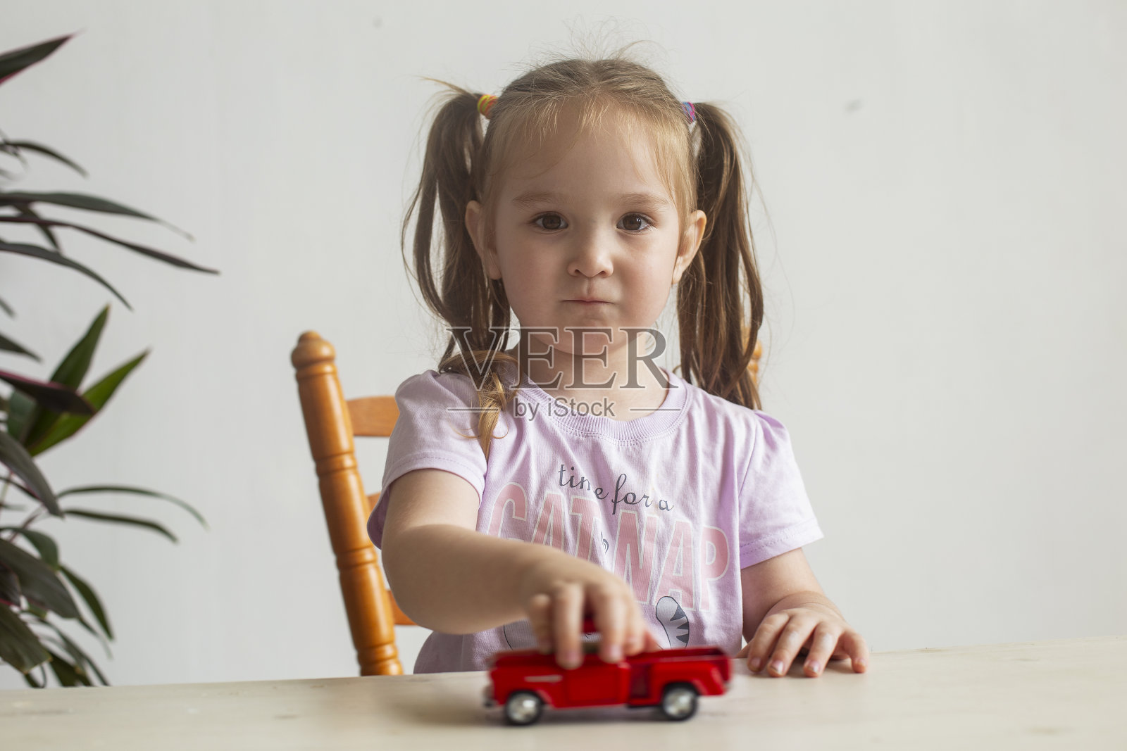 可爱的小女孩在玩红色的小玩具车。照片摄影图片