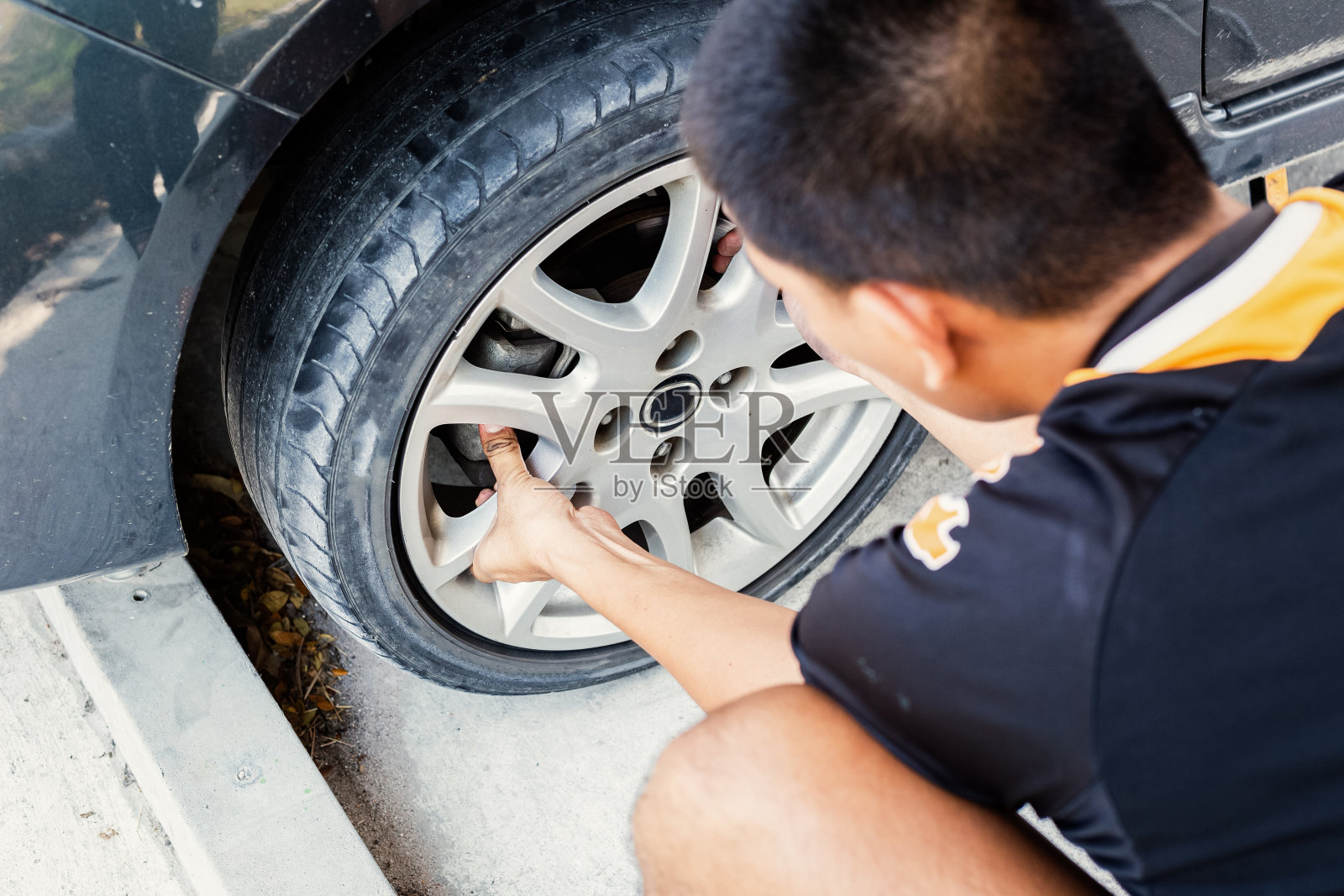 在停车场换轮胎的男人。照片摄影图片