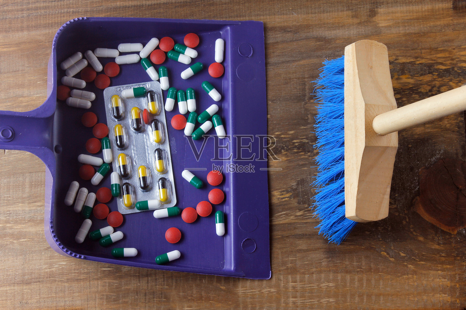 扫帚把药品扔进垃圾桶。摆脱对药物的依赖和解除机体的毒素的概念照片摄影图片