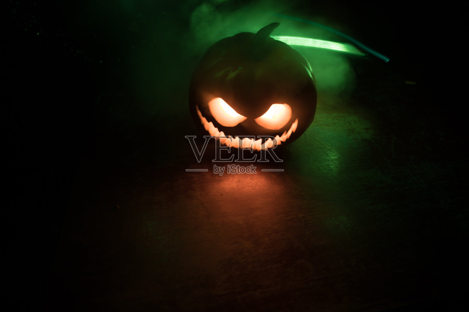 万圣节南瓜微笑和恐怖的眼睛派对之夜。近距离观看可怕的万圣节南瓜与眼睛发光内部在黑色的背景照片摄影图片