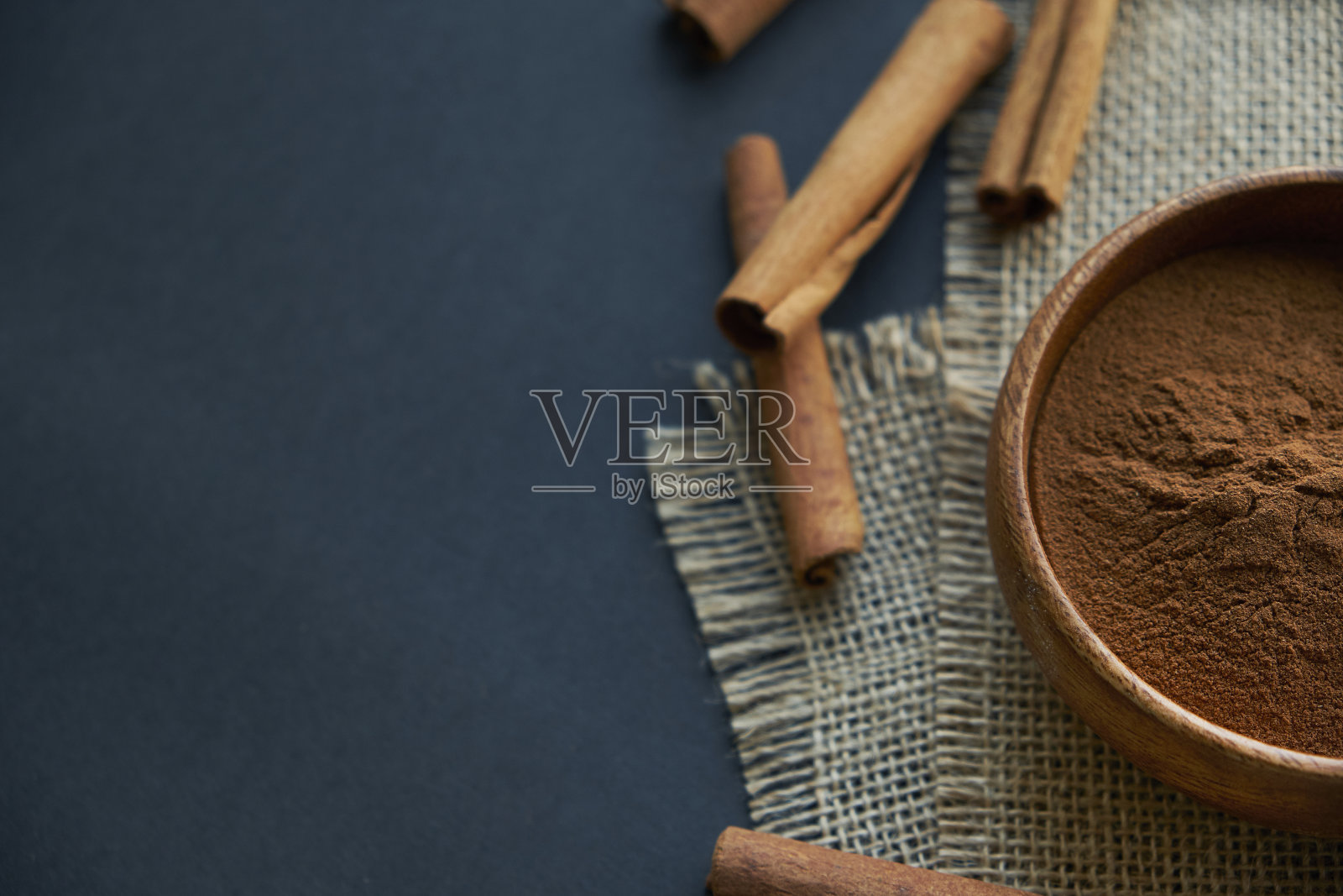 肉桂棒，与黄麻绳系在乡村风格。磨碎的肉桂在一个木碗和古董勺。靠近一个黑色的背景。为文本复制空间。俯视图，平放照片摄影图片