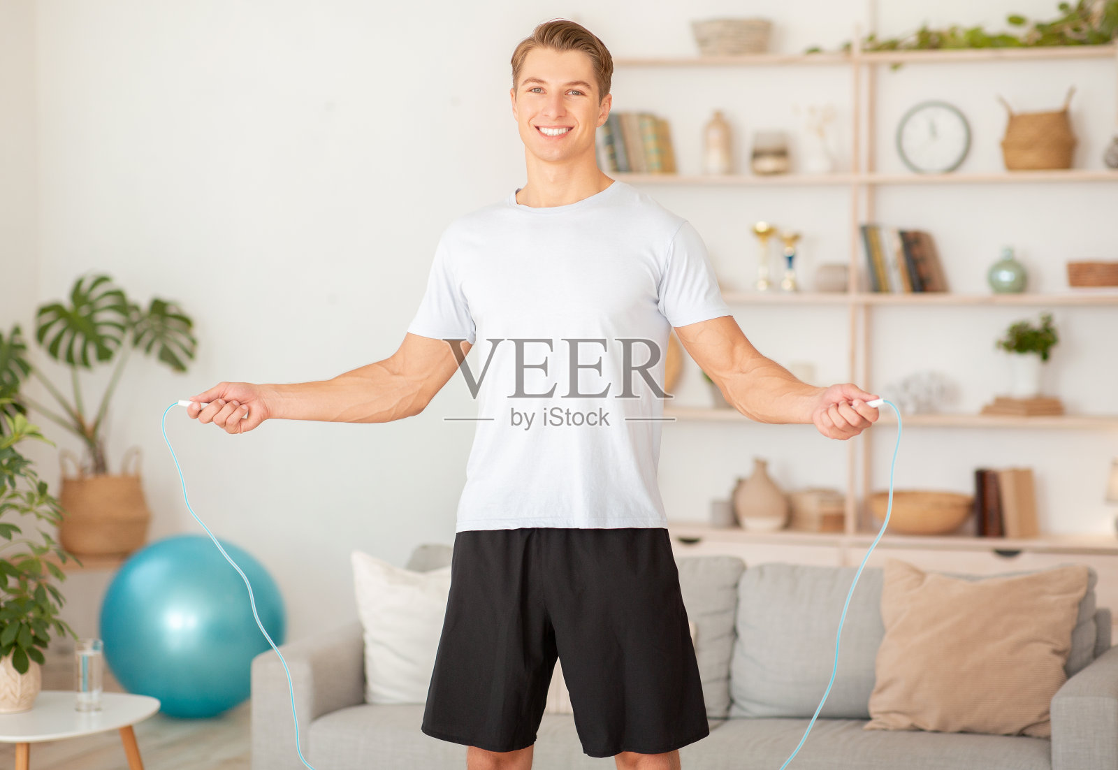 covid-19大流行期间在家进行有氧运动。肌肉发达的男子正在跳绳照片摄影图片