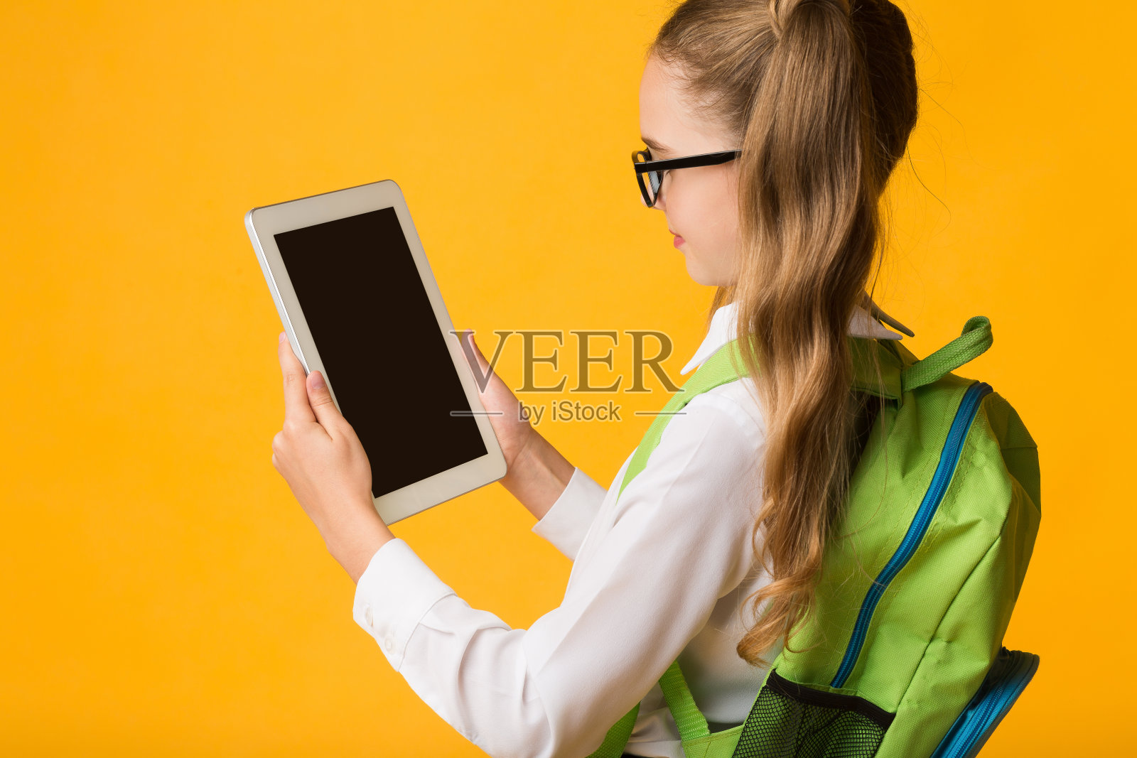 学校女孩与平板电脑使用教育应用程序，黄色背景，模型照片摄影图片