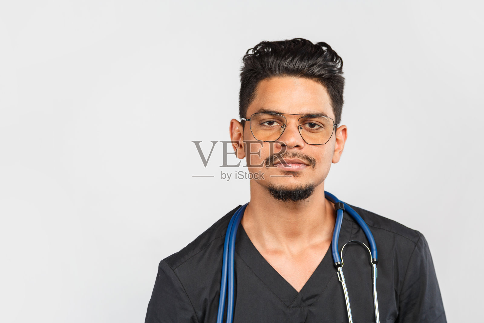 英俊的现代印度/亚洲医生在灰色背景制服听诊器。医学、保健和人的理念照片摄影图片