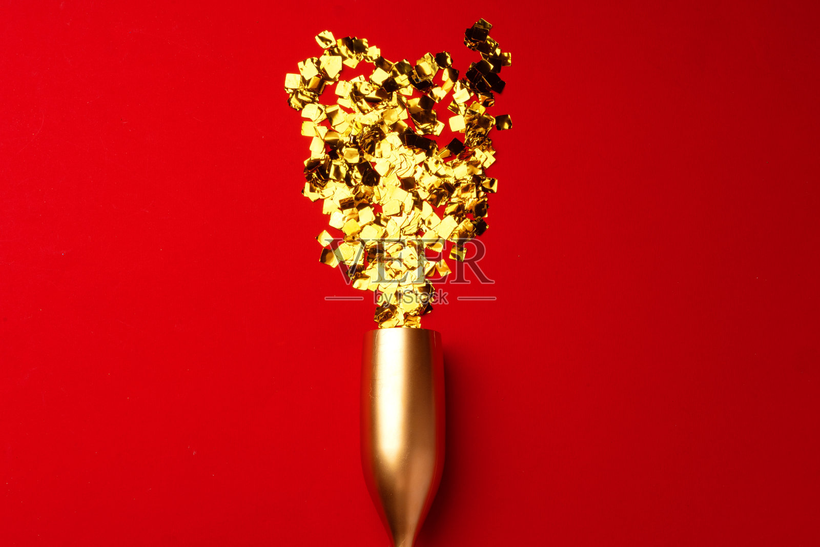 红色背景上撒着五彩纸屑的香槟酒杯平躺着照片摄影图片