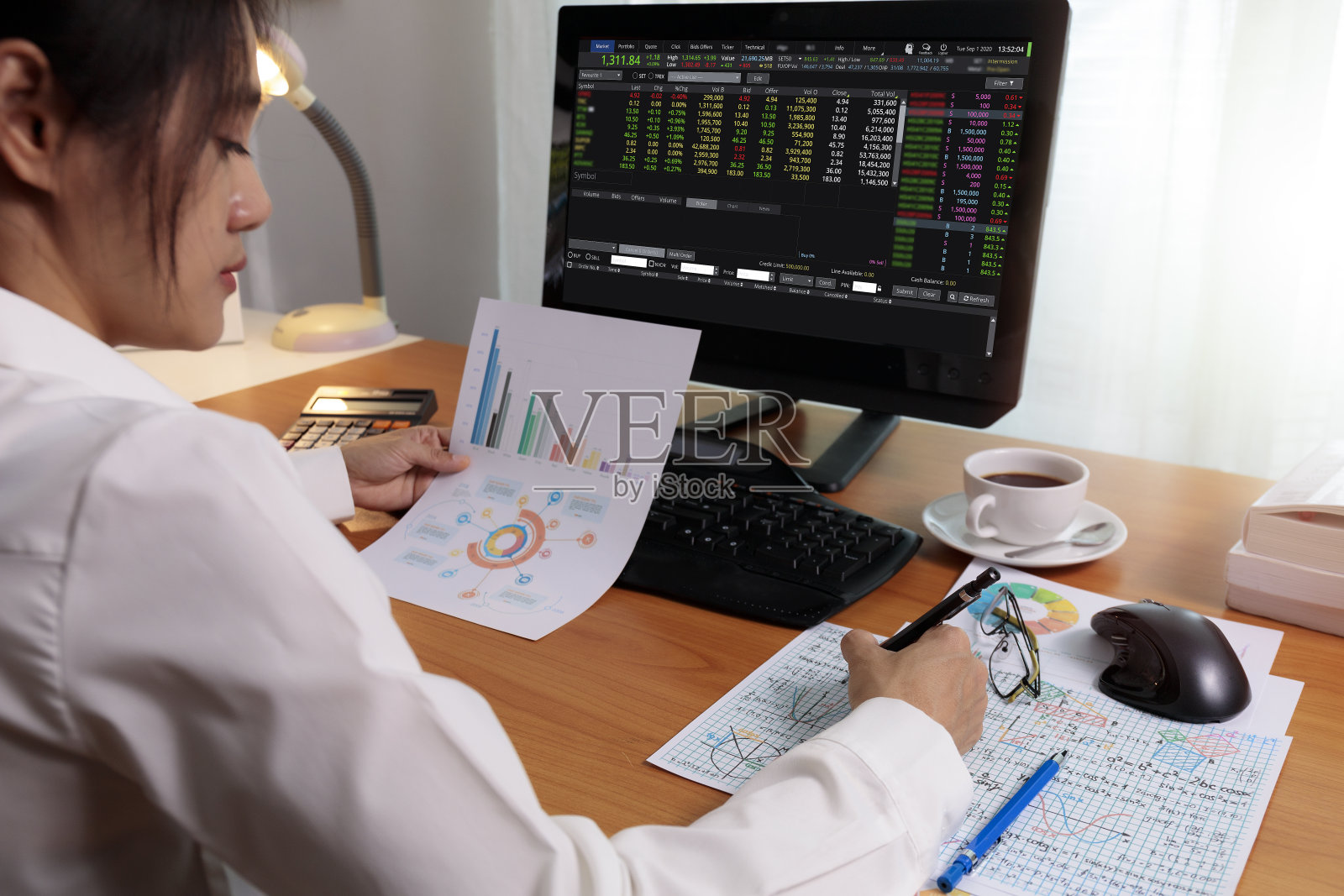 商务女性工作在办公室与电脑持有图表报告纸和看。商务人士在家里用纸和电脑屏幕工作。商业和金融，在家工作的概念照片摄影图片