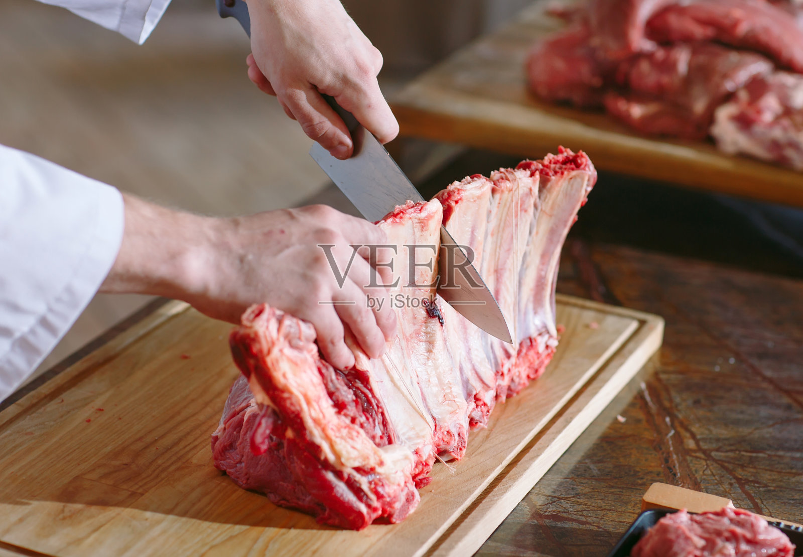 在餐馆里，一个厨师用刀切肉。照片摄影图片