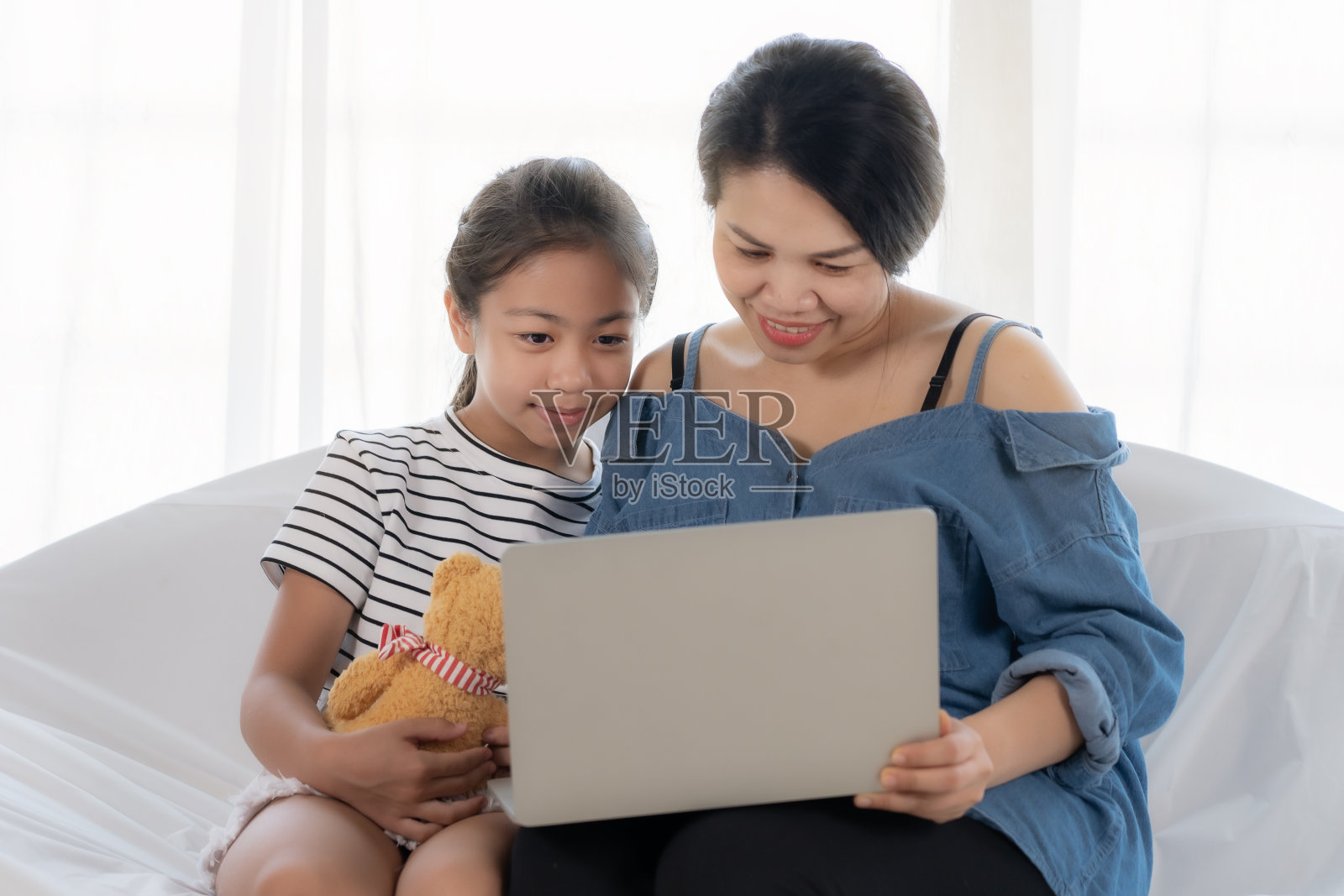 母女俩在用笔记本电脑。照片摄影图片