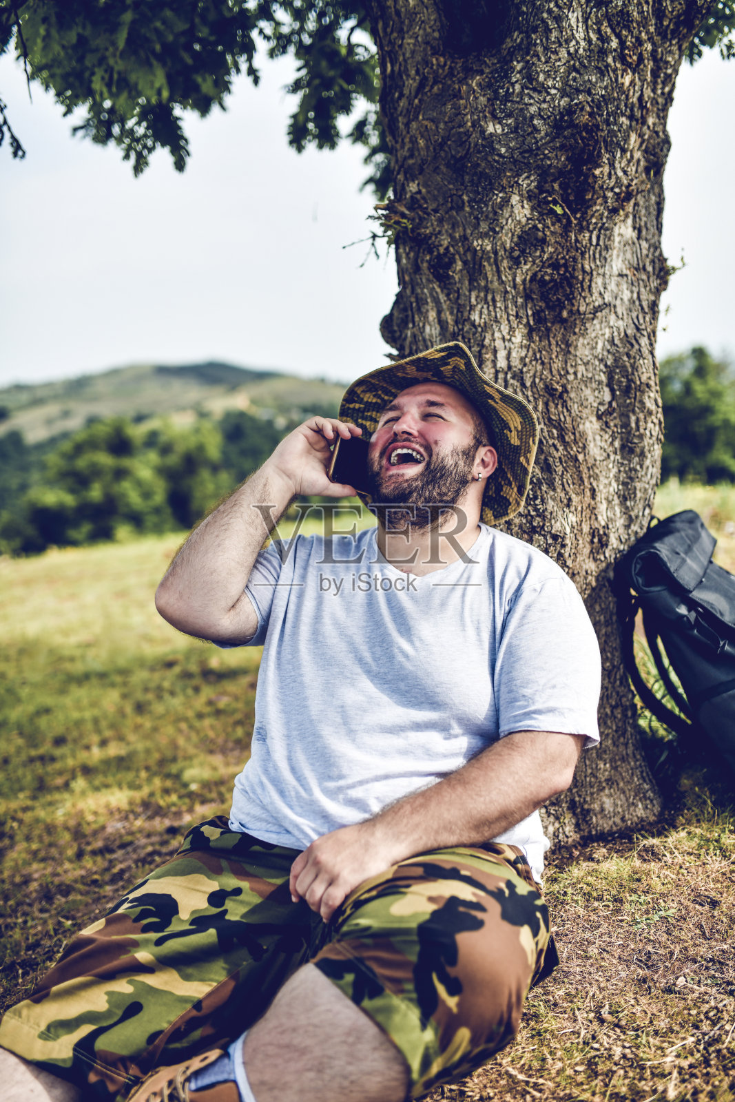 男性徒步旅行者在打电话休息时大笑照片摄影图片