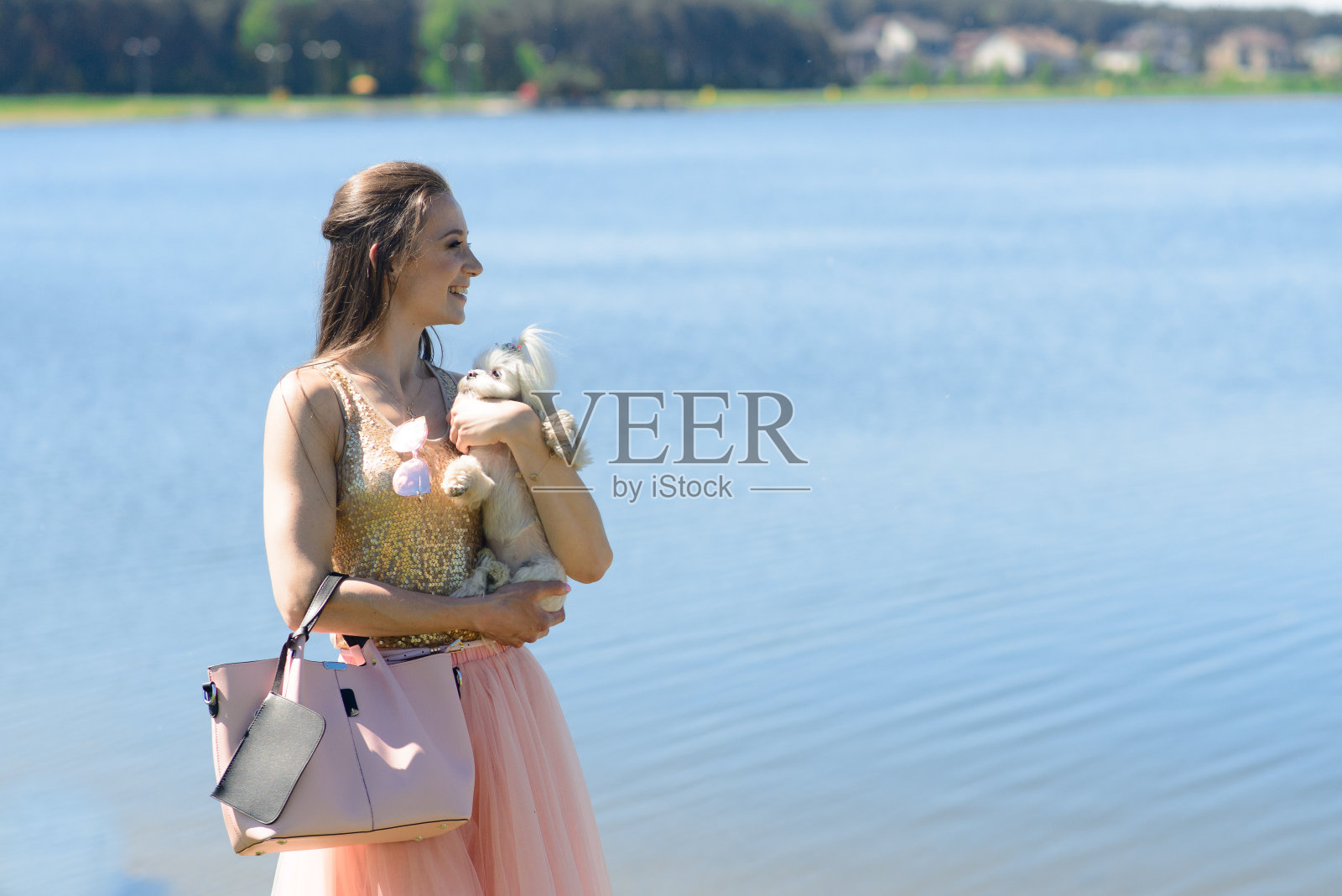 一个年轻女人和她的狗。一只白色的小狗和它的主人一起跑。关于友谊、动物和自由的概念。照片摄影图片