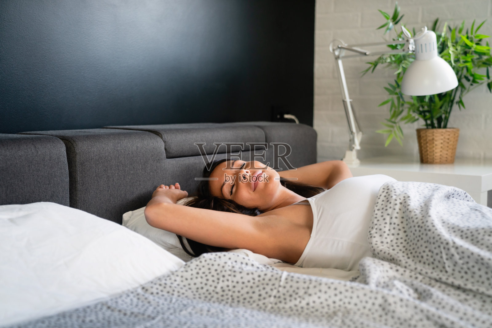 早上醒来后，女人在床上伸懒腰照片摄影图片