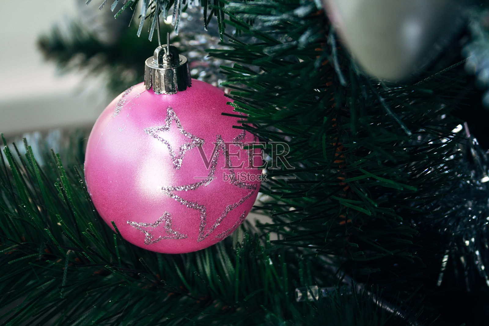 粉红色的球在人造圣诞树上。有选择性的重点。新年前夕装饰的节日卡片照片摄影图片