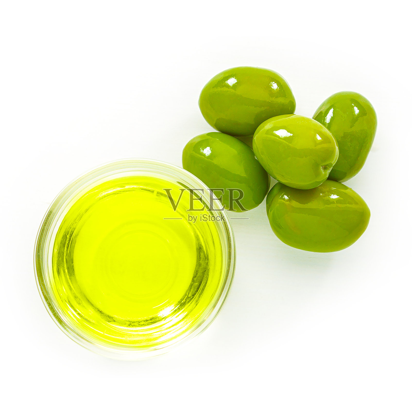 白色背景上放着一大颗绿橄榄和一个盛有橄榄油的玻璃碗。特写镜头前视图。照片摄影图片