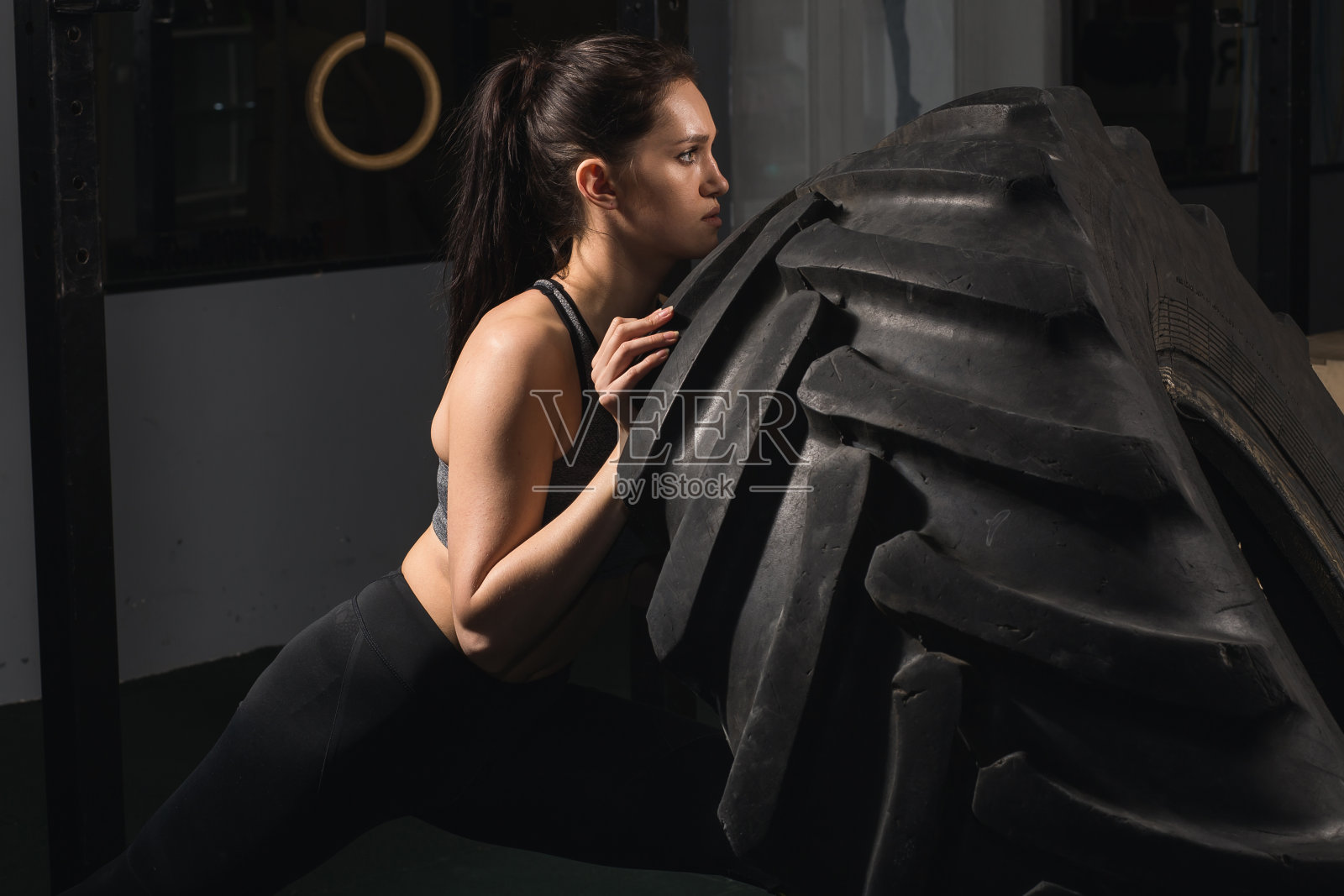 坚强的女孩在健身房甩轮胎。照片摄影图片