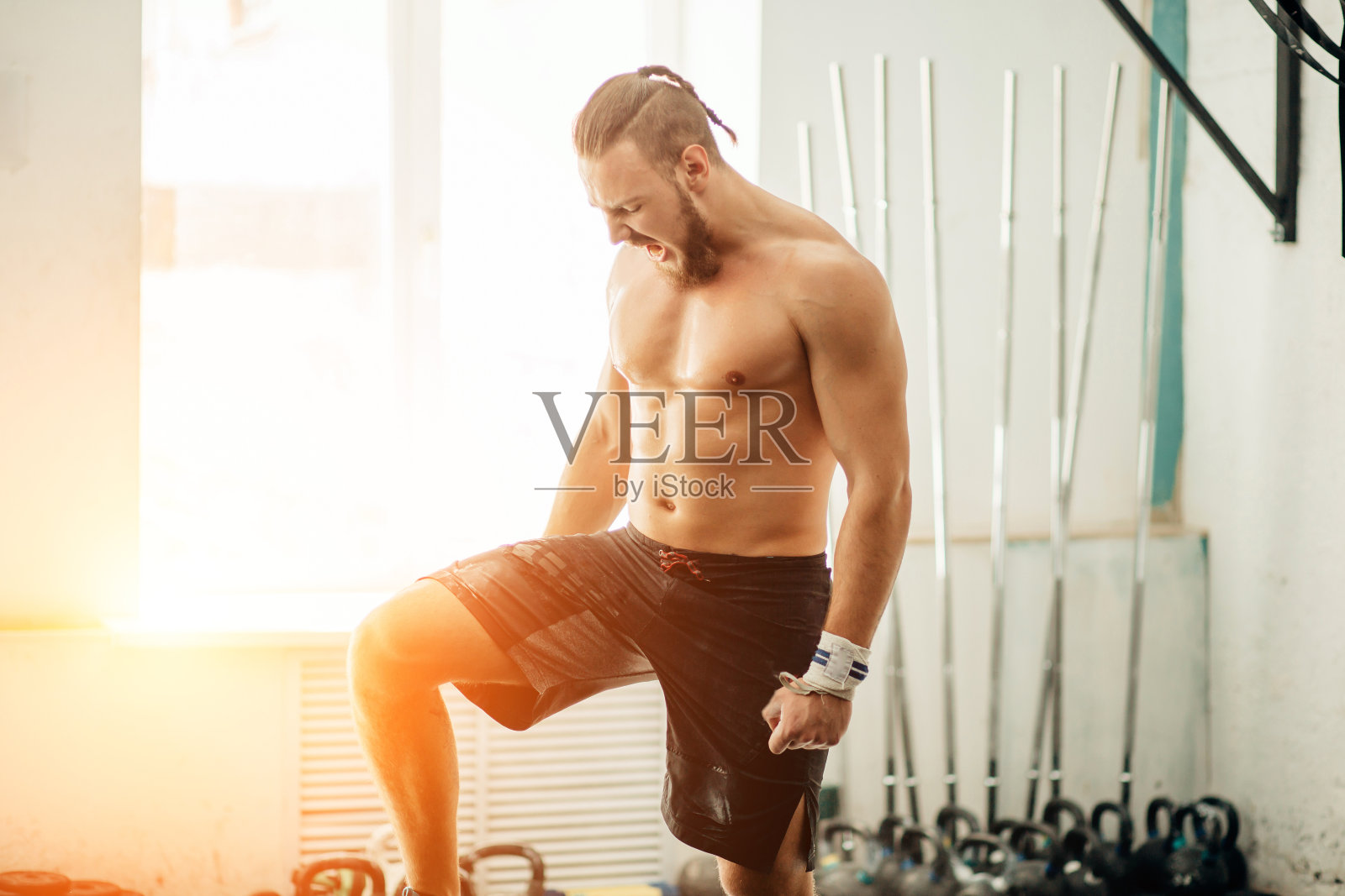 一个年轻人在健身房准备练杠铃。把他的腿放在杠铃上照片摄影图片