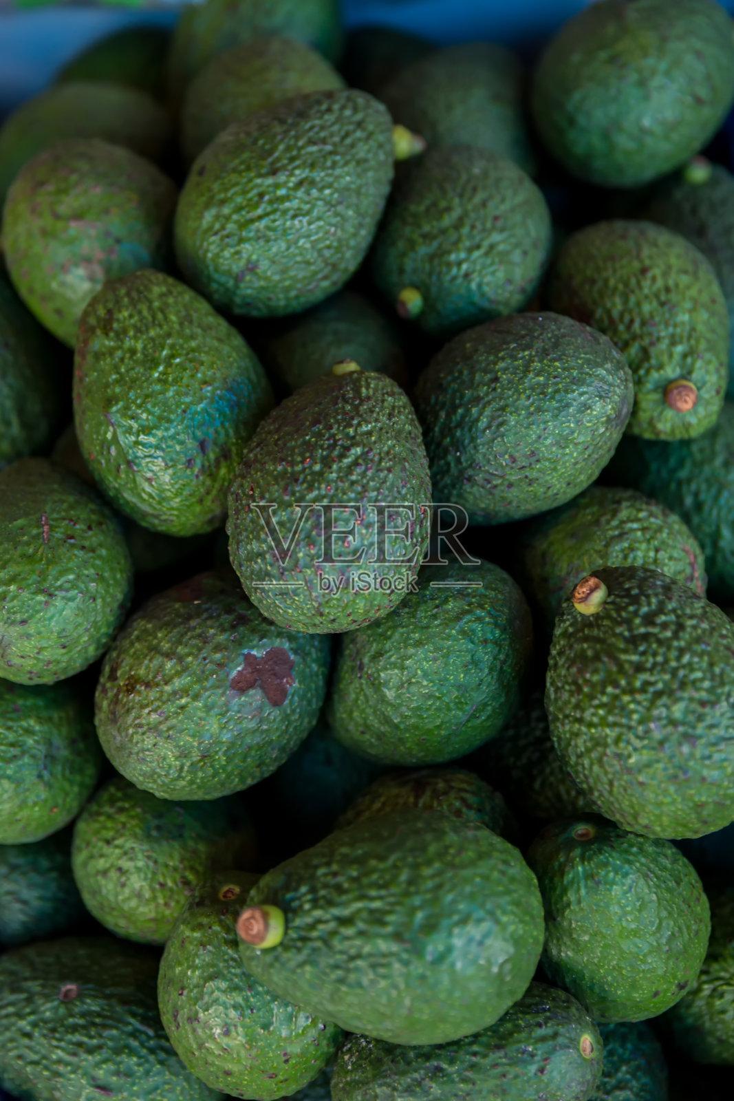 当地市场的新鲜牛油果。新鲜市场上有成堆的牛油果在卖。绿色的鳄梨水果堆在泰国的街道上出售。照片摄影图片