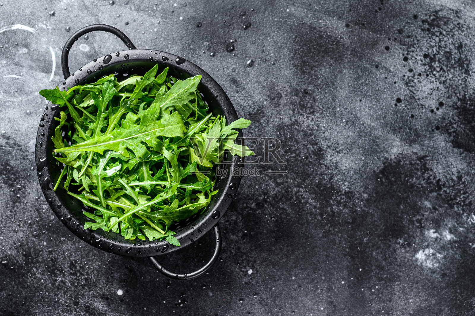 新鲜的rucola叶子在滤锅。黑色背景。前视图。本空间照片摄影图片