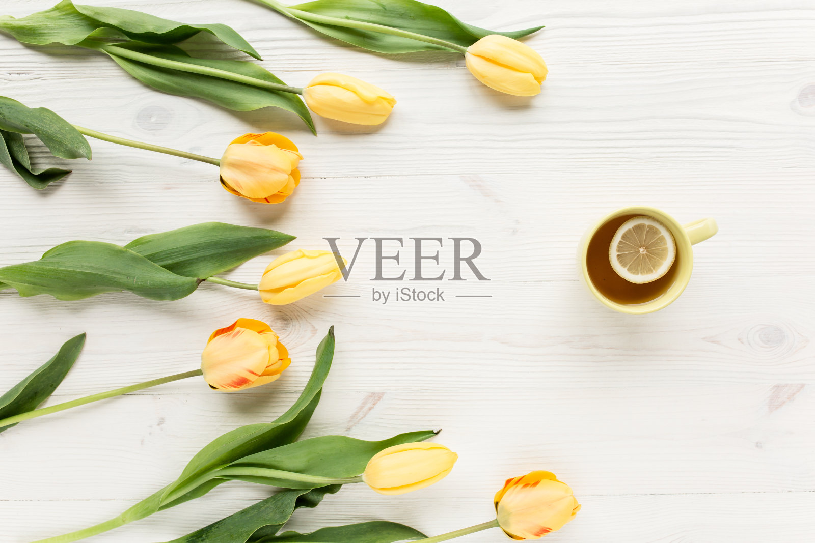 黄色的郁金香，一杯孤立在白色木质背景上的茶。平放，俯视图照片摄影图片