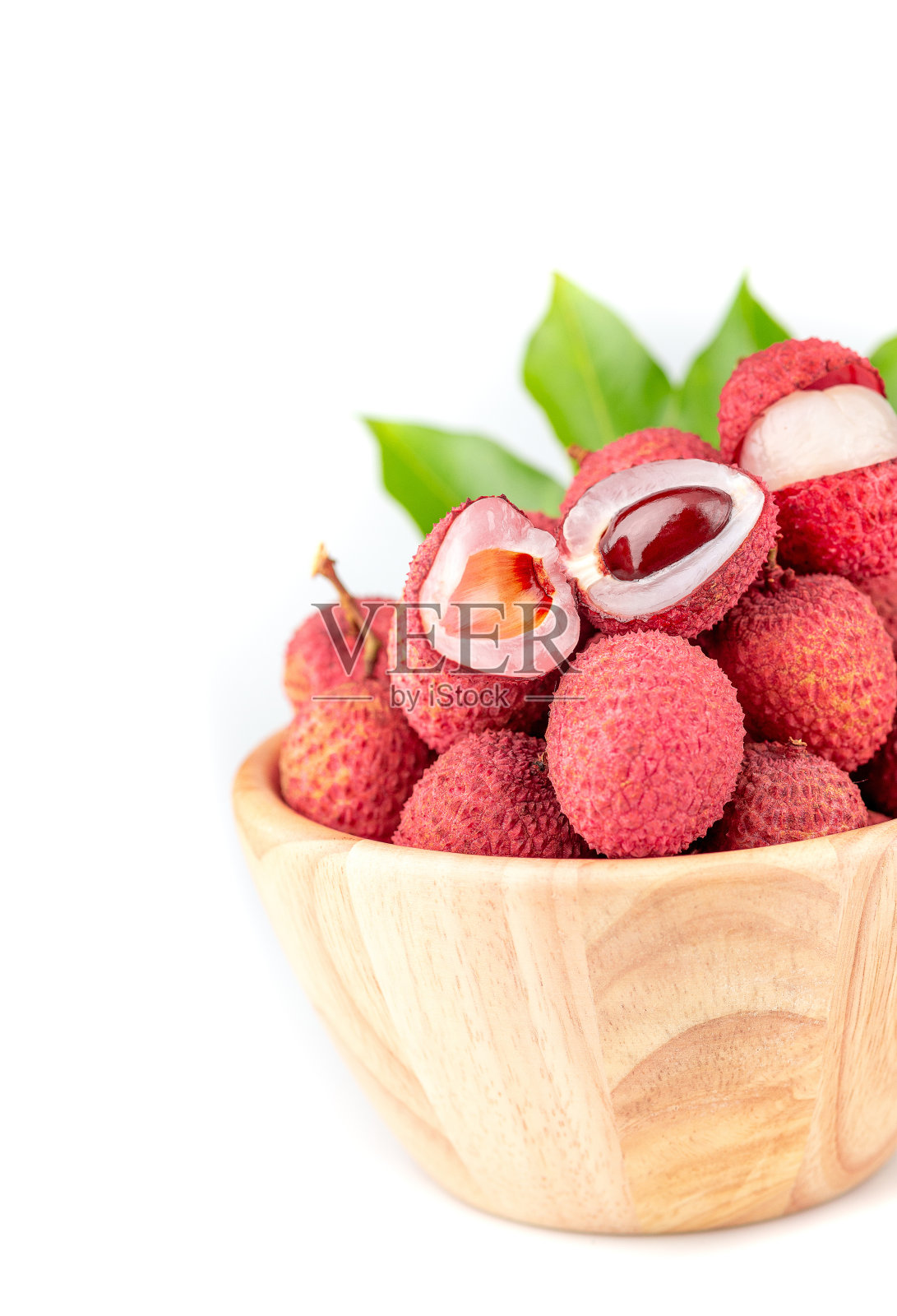 荔枝洪辉在一个木碗里，枝叶绿油油的，在白色的背景上孤立地夹着小路照片摄影图片
