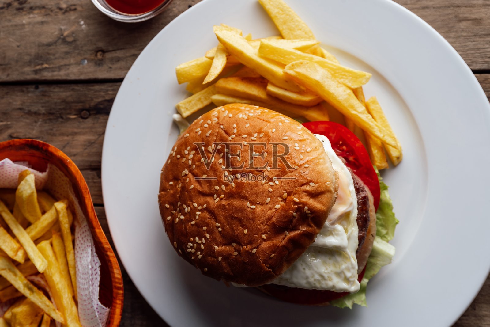 简陋的木桌上放着鸡蛋和土豆的汉堡照片摄影图片