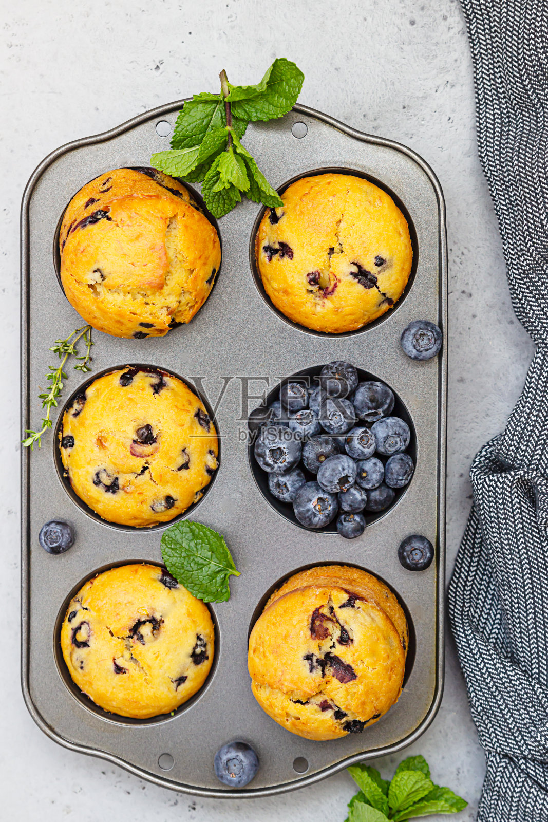 新鲜烘焙的蓝莓松饼配上百里香和薄荷。灰石的背景。照片摄影图片