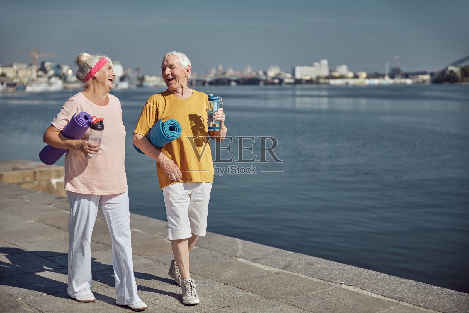 快活的退休老人胳膊下夹着卷起的垫子照片摄影图片