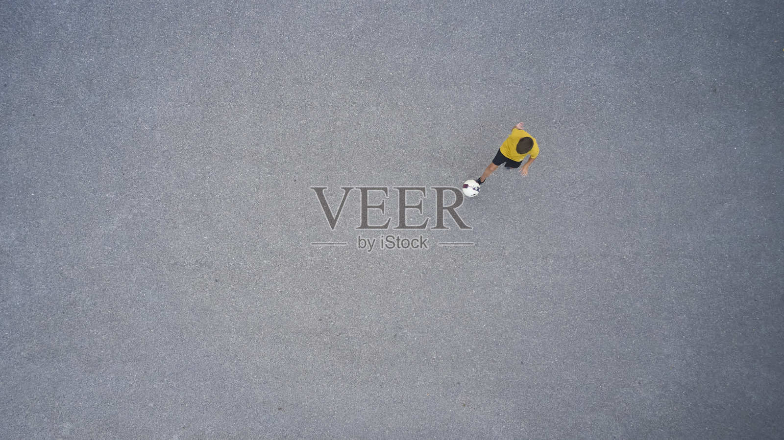 男孩在街上踢足球照片摄影图片