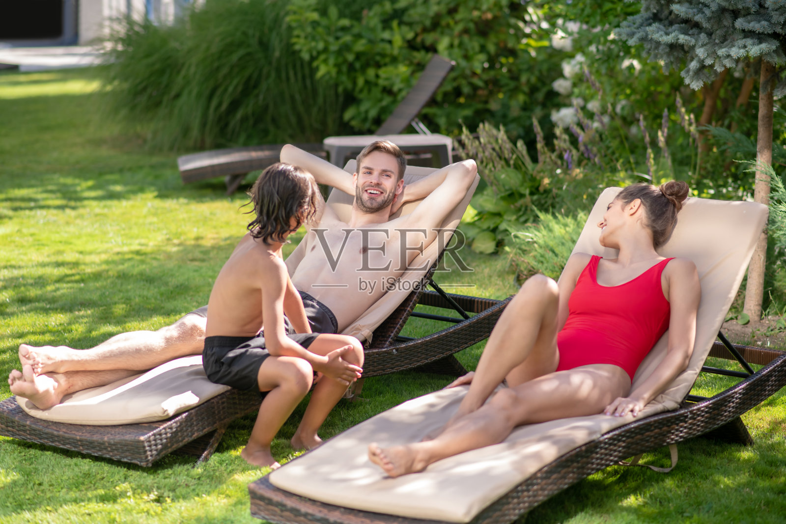 爸爸妈妈和儿子在日光浴床上休息照片摄影图片