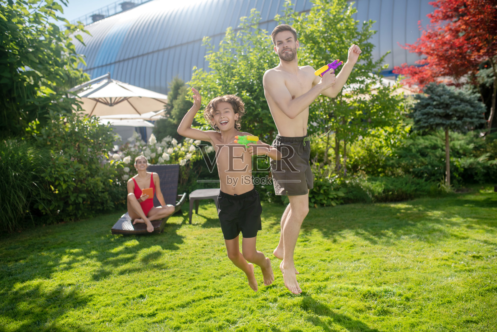 儿子和爸爸拿着水枪跳了起来照片摄影图片