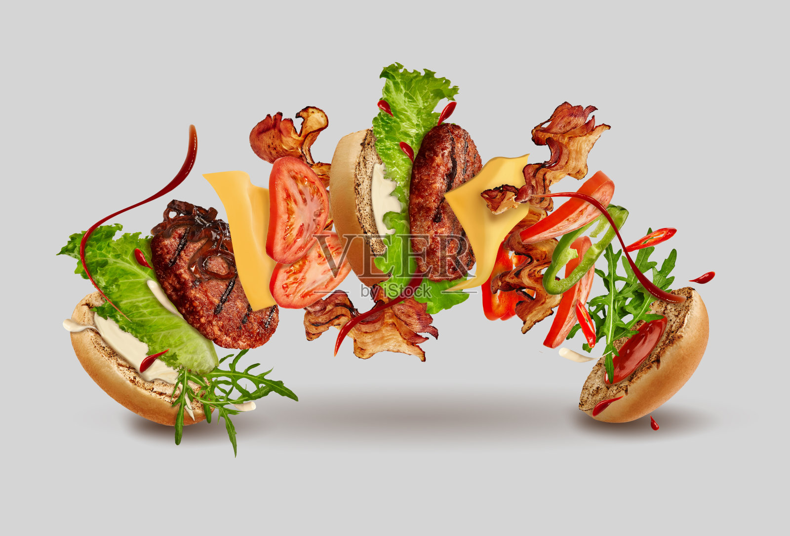 汉堡与飞行的配料，以灰色背景。火腿，牛肉片，芝士，番茄酱，蛋黄酱，蔬菜和青菜。关闭，复制空间照片摄影图片