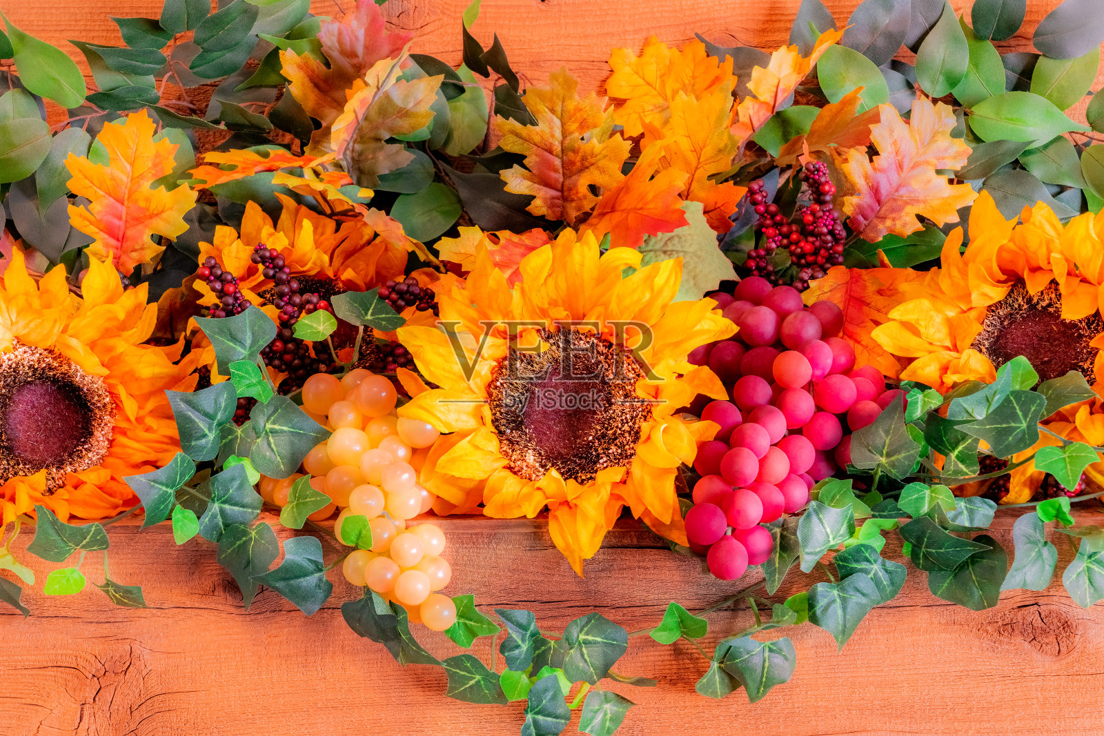 向日葵、葡萄和秋天的树叶摆满了装饰好的感恩节壁炉架。照片摄影图片