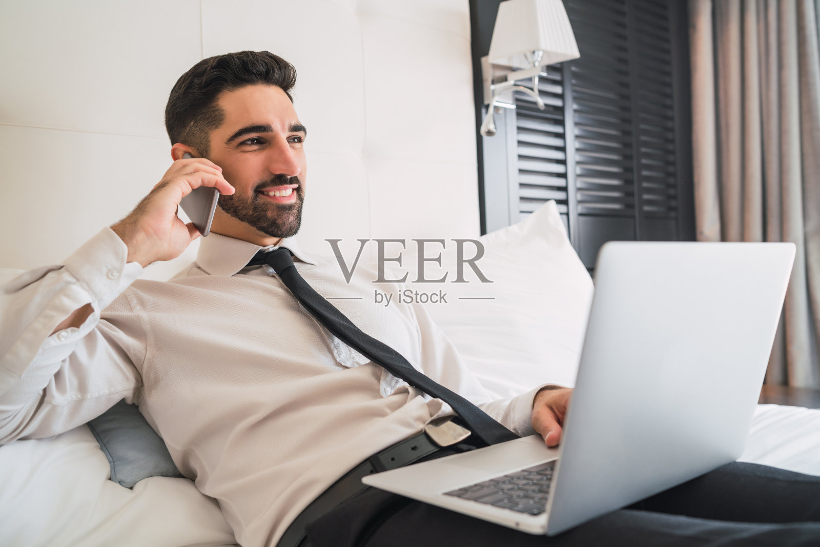 在酒店房间里打电话的商人。照片摄影图片