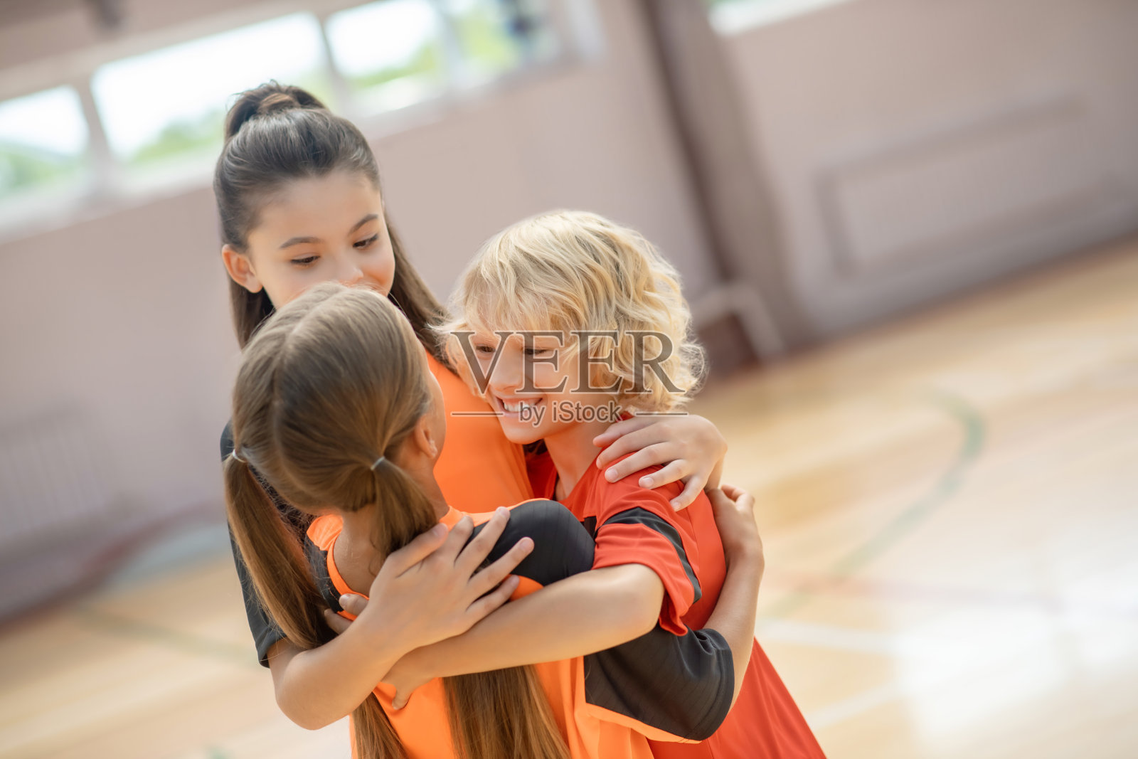 孩子们穿着鲜艳的运动服，拥抱着，看起来很开心照片摄影图片