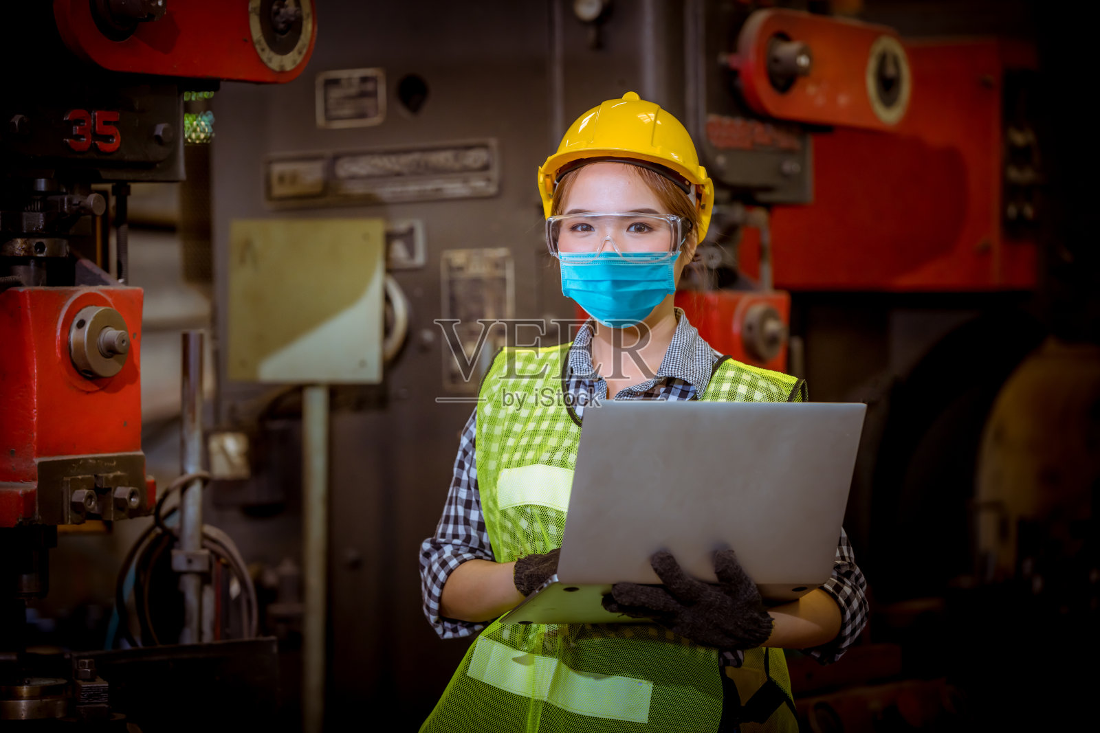 拍摄女工在工厂工位上被检查和检查生产过程，戴上安全口罩，保护工厂免受污染和病毒。照片摄影图片