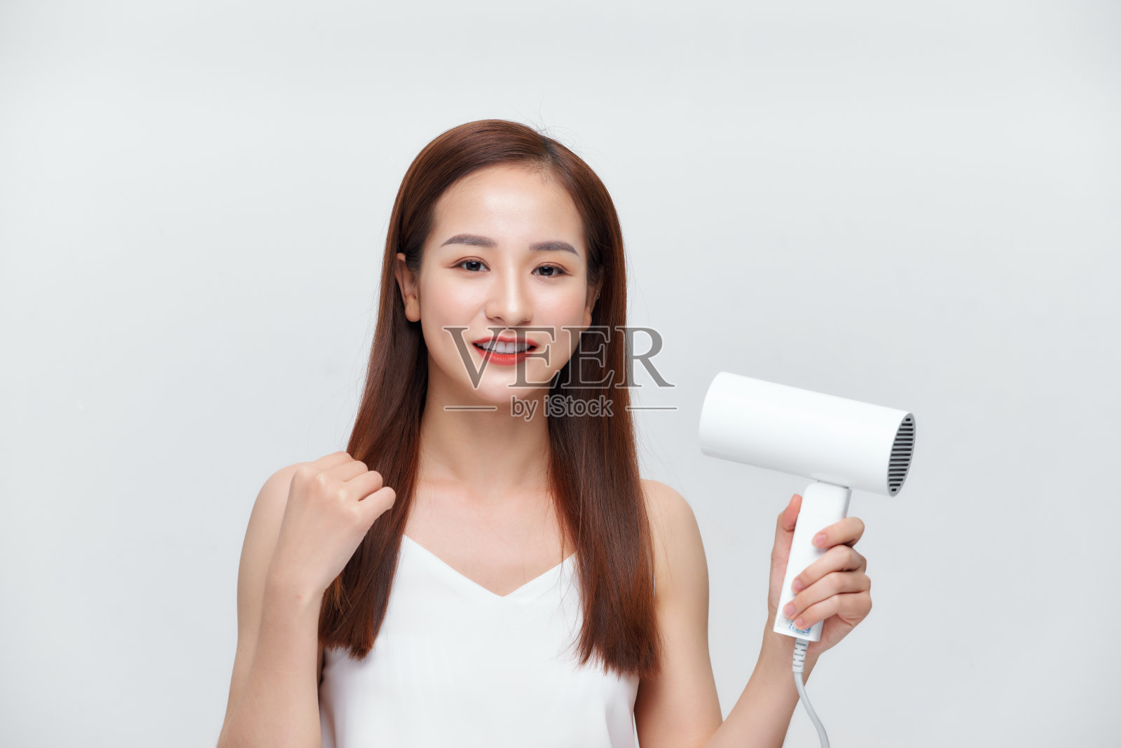 美丽的女孩正在用吹风机吹头发照片摄影图片