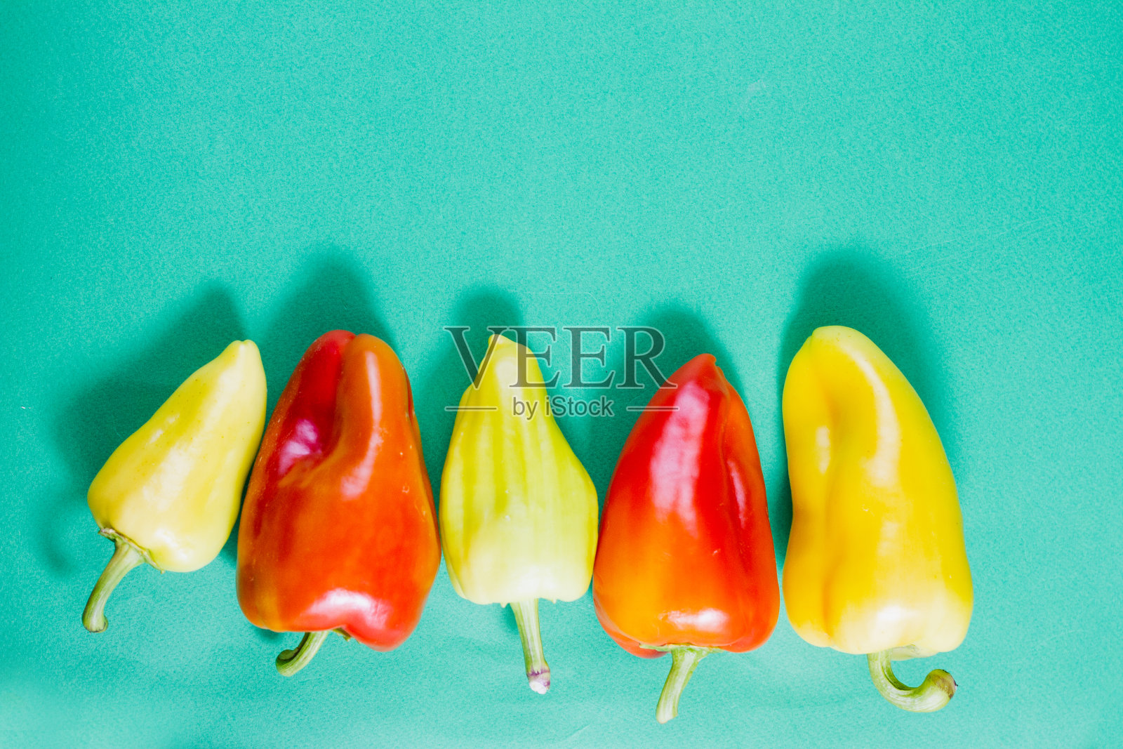 一组成熟的多色柿子椒在柔和的绿色背景上。照片摄影图片