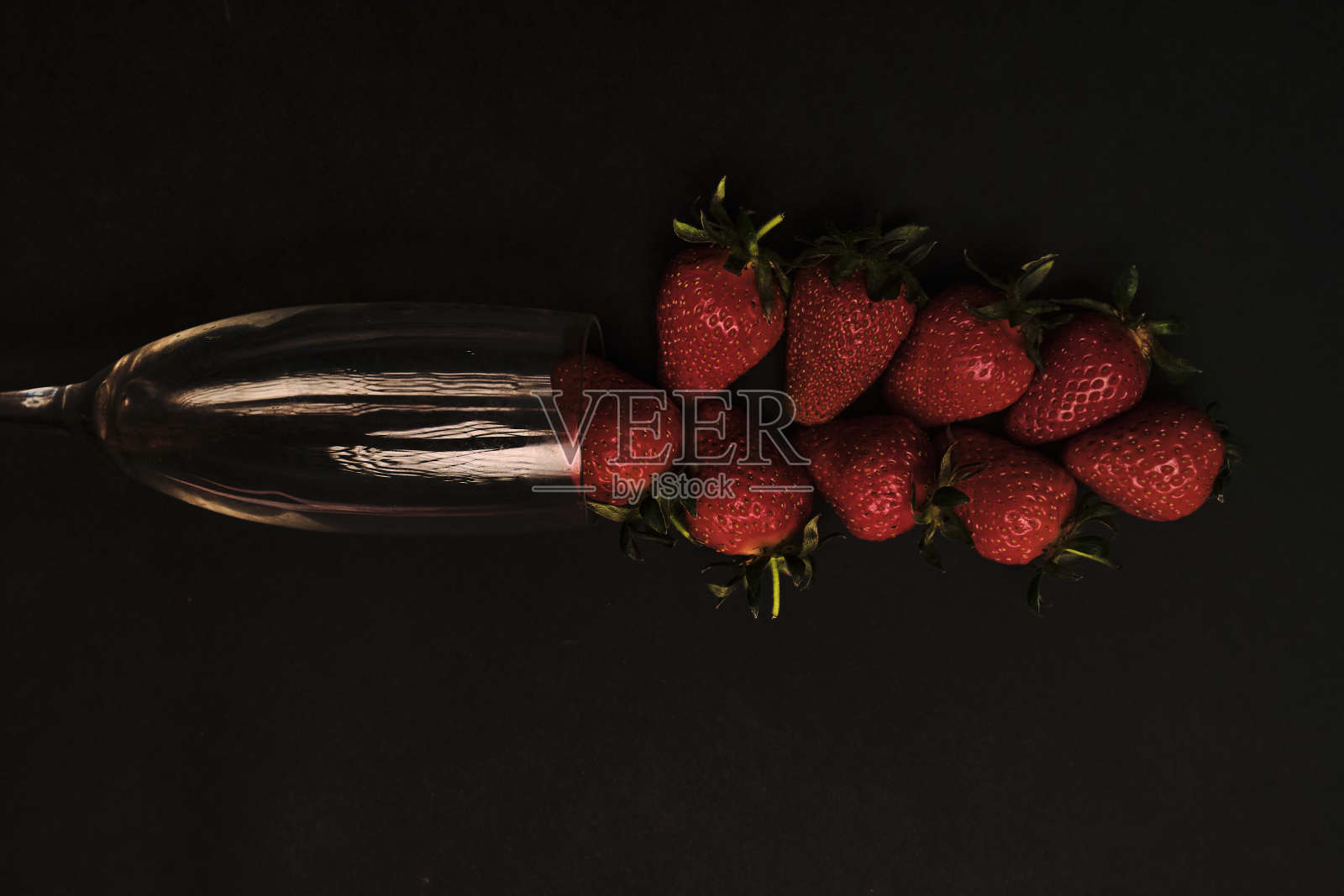 草莓在玻璃上的黑色背景，轻微曝光不足照片摄影图片