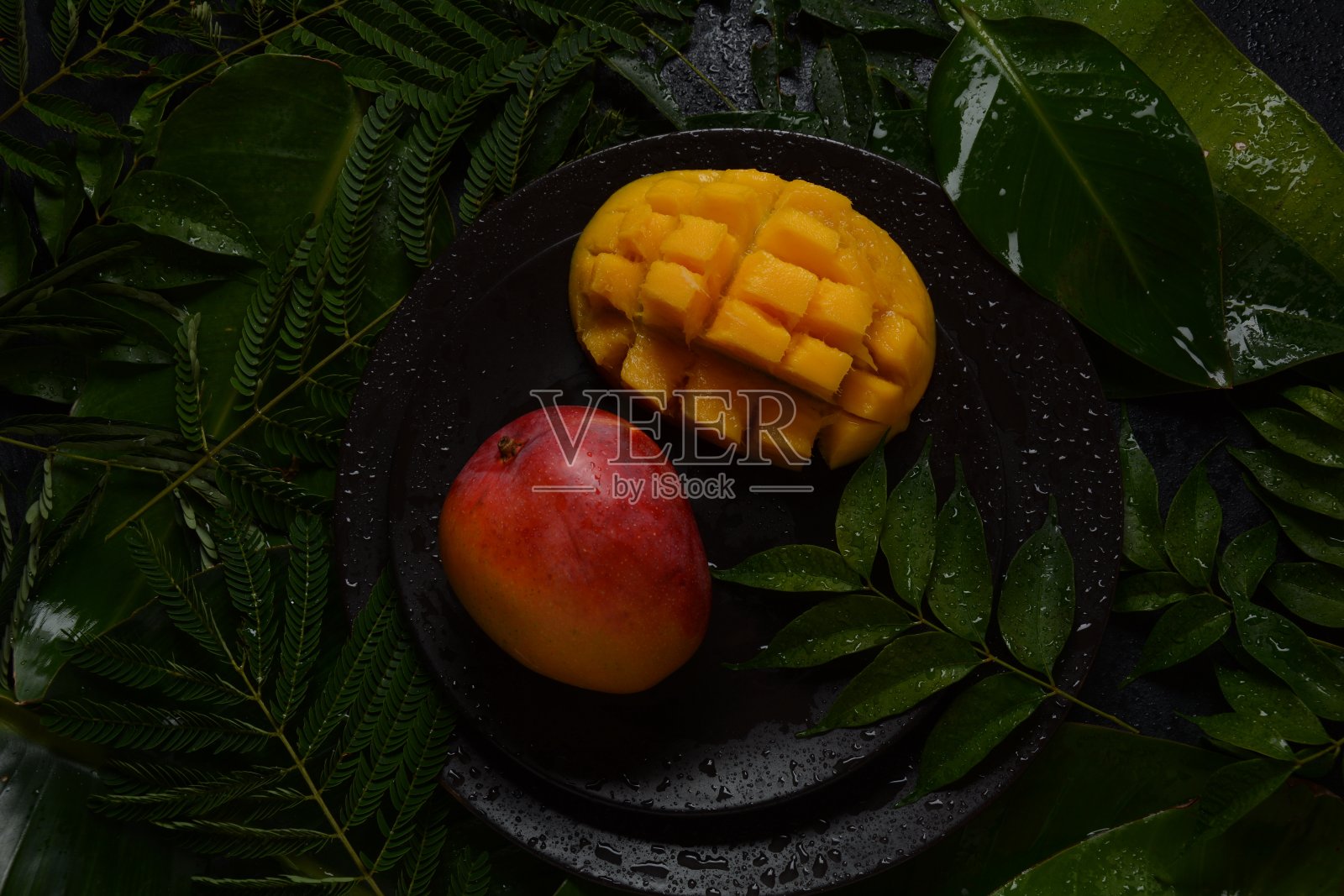 盘中或树叶上的新鲜芒果块照片摄影图片